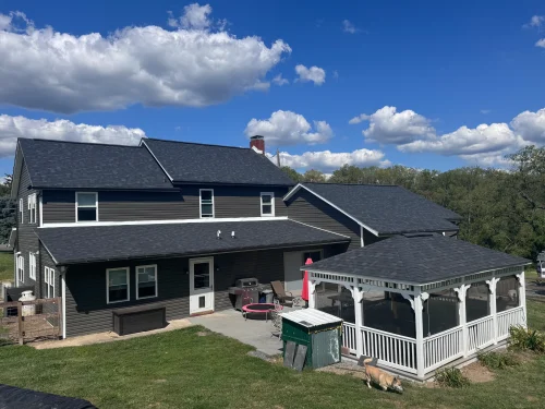 Residential roof replacement with charcoal asphalt shingles on a farmhouse and matching gazebo roof