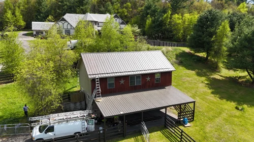 Aerial view of a crew installing a new metal roof on a barn-style garage and attached carport in Pennsylvania