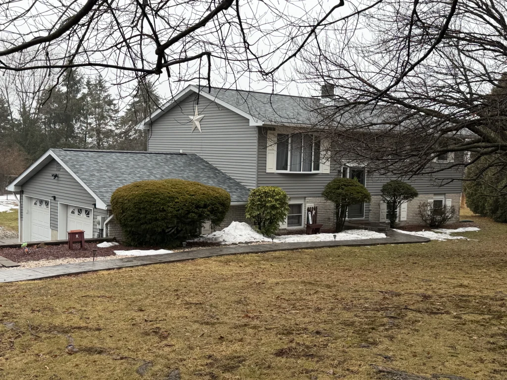 Split-level home with a new gray asphalt shingle roof, gray vinyl siding, and attached two-car garage